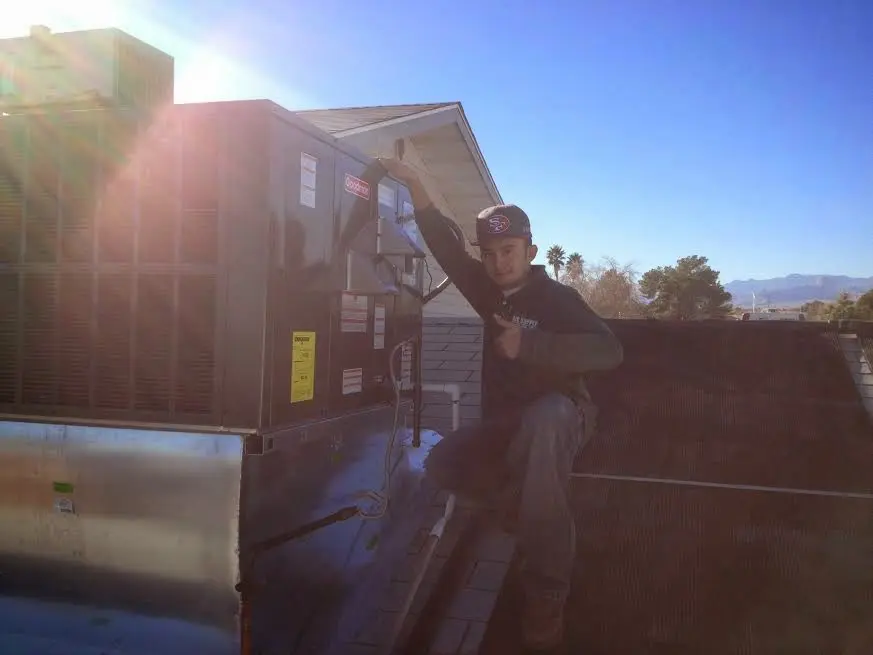 HVAC technician performing Air Duct Cleaning on a rooftop unit in Wayne